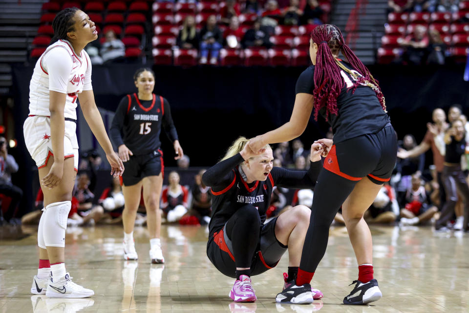 UNLV forward Alyssa Brown (44) reacts as San Diego State guard Abby Prohaska (24) is helped up by guard Mia Davis during the first half of an NCAA college basketball game for the championship of the Mountain West women's tournament Wednesday, March 13, 2024, in Las Vegas. (AP Photo/Ian Maule)