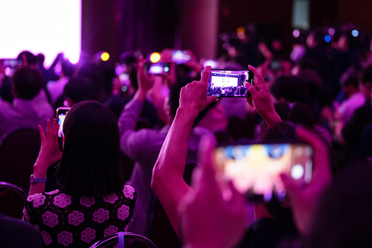 People hold phones into the air to photograph Sam Altman during an event in South Korea (SeongJoon Cho / Bloomberg via Getty Images)