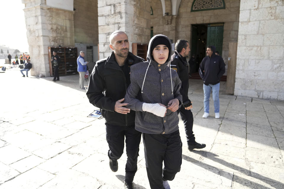 An Israeli police officer leads a Palestinian youth out of the Al-Aqsa Mosque compound following a raid of the site in the Old City of Jerusalem during the Muslim holy month of Ramadan, Wednesday, April 5, 2023. Palestinian media reported police attacked Palestinian worshippers, raising fears of wider tension as Islamic and Jewish holidays overlap.(AP Photo/Mahmoud Illean)