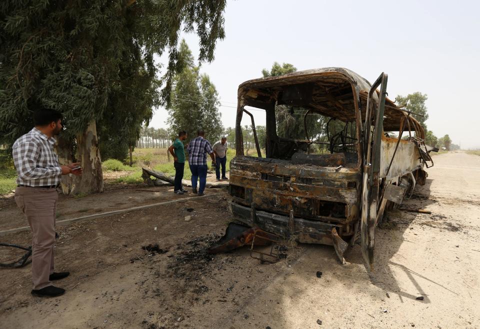 People look at a burnt bus in Taji, north of Baghdad July 24, 2014. A shooting and bombing attack on a bus near Baghdad killed 52 prisoners and nine policemen on Thursday, Ministry of Justice and medical sources said, the latest in a string of assaults on prisoners in Iraq. The motive for Thursday's killings was not immediately clear but Iraqi security forces and government affiliated Shi'ite militias appear to have unlawfully executed at least 255 prisoners over the past month in apparent revenge for killings by Sunni militants, according to Human Rights Watch. The bus was transporting prisoners from a military base in the town of Taji to Baghdad when it was hit by roadside bombs, the sources said. Gunmen then opened fire. (REUTERS/Thaier al-Sudani)
