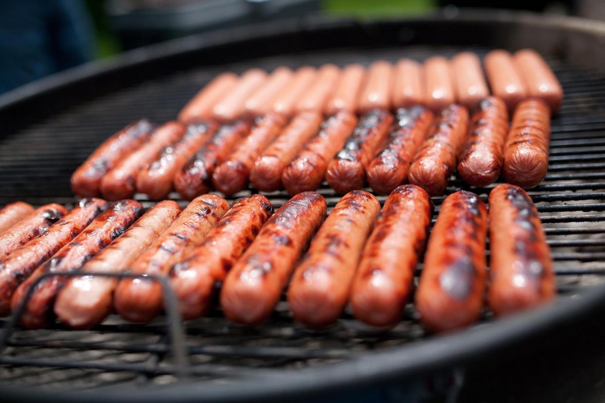 several blackened hot dogs cooking on a grill
