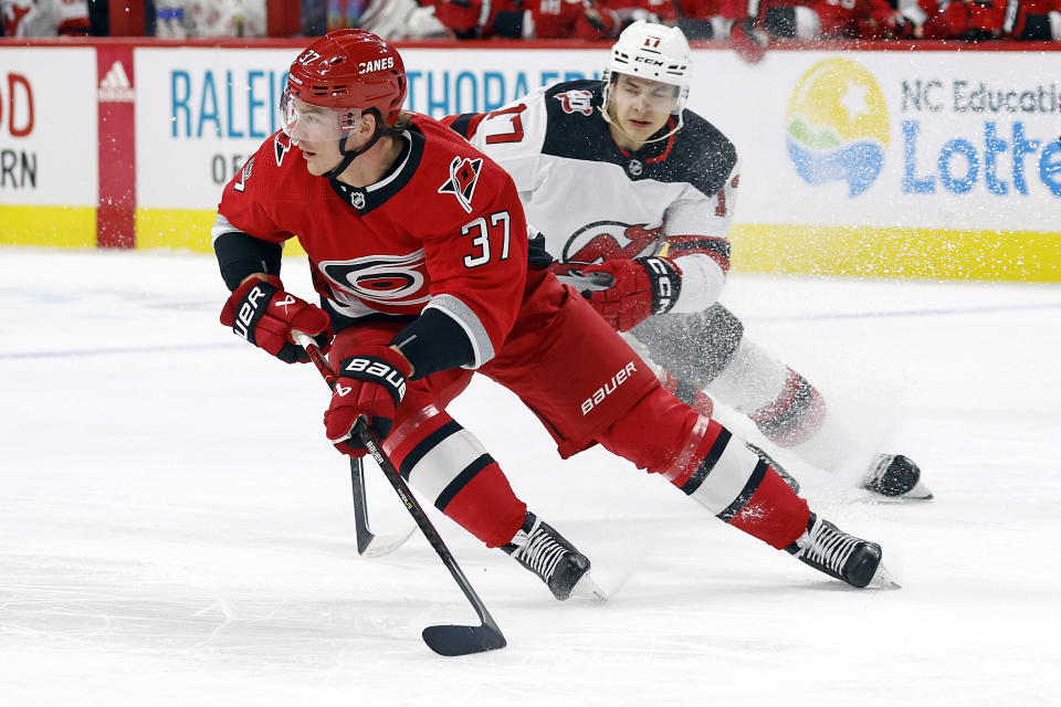 Carolina Hurricanes' Andrei Svechnikov (37) skates with the puck away from New Jersey Devils' Yegor Sharangovich during the first period of an NHL hockey game in Raleigh, N.C., Tuesday, Dec. 20, 2022. (AP Photo/Karl B DeBlaker)