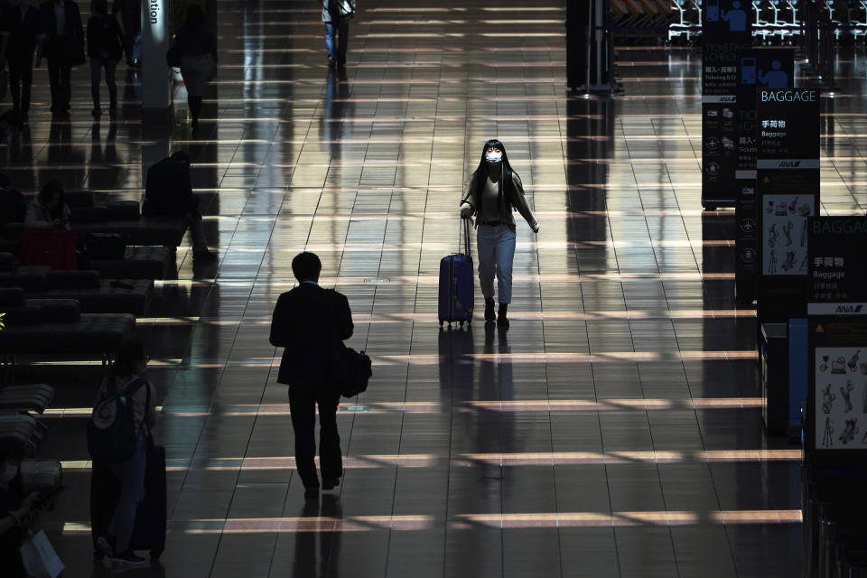 FILE - In this April 29, 2020, file photo, a few passengers walk at a domestic terminal of Haneda Airport in Tokyo, at the start of "Golden Week" holidays. Under Japan's coronavirus state of emergency, people have been asked to stay home. Many are not. Some still have to commute to their jobs despite risks of infection, while others are dining out, picnicking in parks and crowding into grocery stores with scant regard for social distancing. (AP Photo/Eugene Hoshiko, File)