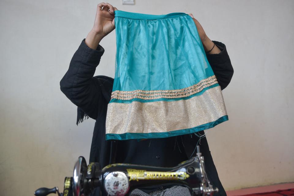 Una de las hijas de Marwa cose ropa durante la entrevista. (Photo by LUANA SARMINI-BUONACCORSI/AFP via Getty Images)