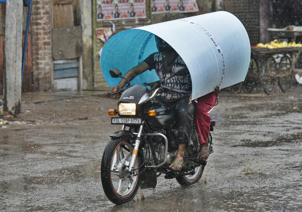 Commuters cover their heads with a plastic sheet amid light showers in Brijpuri,  on August 5, 2020 in New Delhi, India. (Photo by Biplov Bhuyan/Hindustan Times via Getty Images)