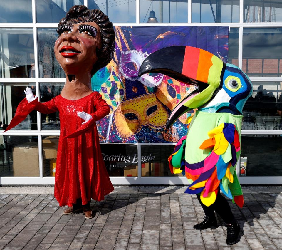 An Aretha Franklin paper-mache head and a toucan head from the Parade Company dance to music during the Detroit Riverfront Conservancy's Winter at Valade Mardi Gras celebration at Robert C. Valade Park in Detroit on Feb. 26, 2022.