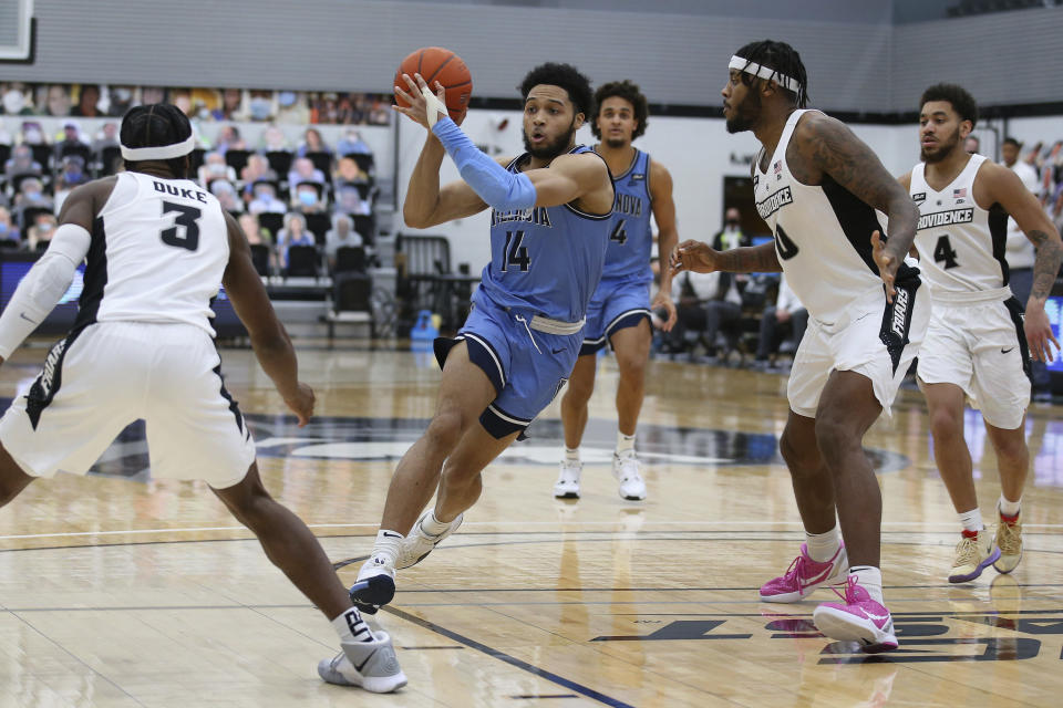 Villanova's Caleb Daniels (14) drives to the basket as Providence's David Duke (3) and Nate Watson (0) defend during an NCAA college basketball game in Providence, R.I., Saturday, March 6, 2021. (AP Photo/Stew Milne)