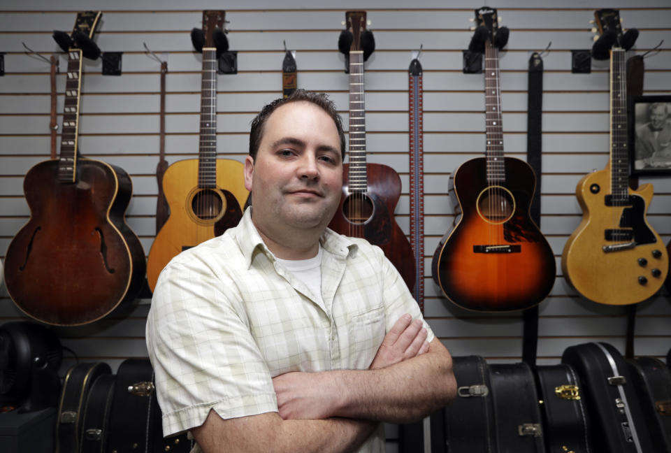 Jacob Tuel, owner of Burning River Guitars, poses for a photo in his workshop, Monday, June 10, 2019, in Akron, Ohio. Tuel named his guitar shop after the 1969 blaze on the Cuyahoga River, in Cleveland. (AP Photo/Tony Dejak)