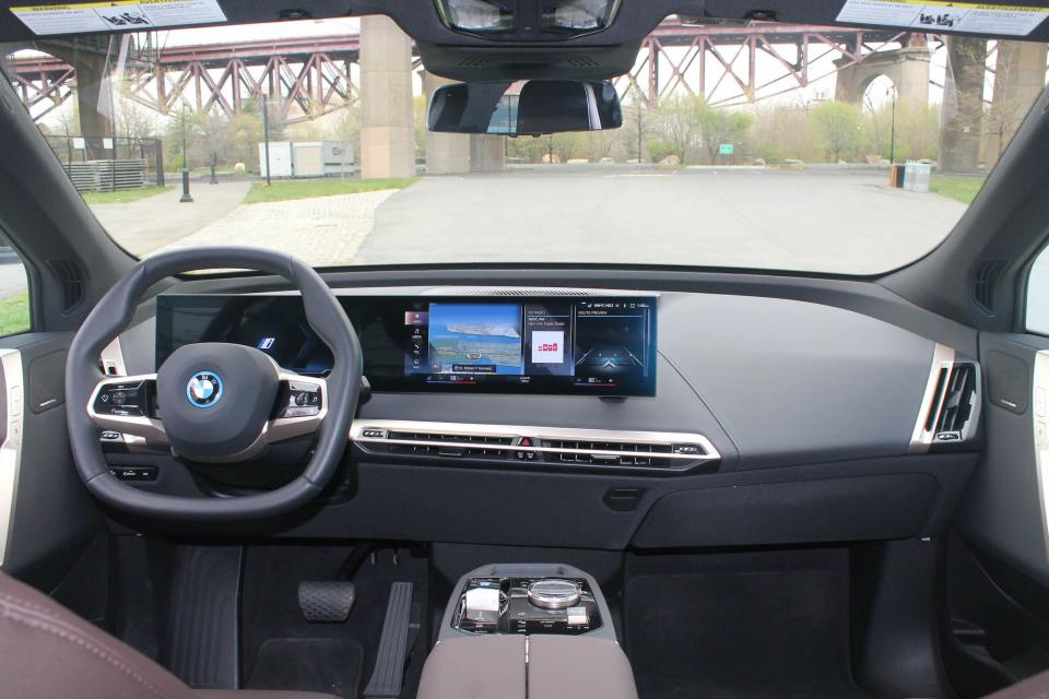 The steering wheel, touchscreen, and windshield of the BMW iX SUV.