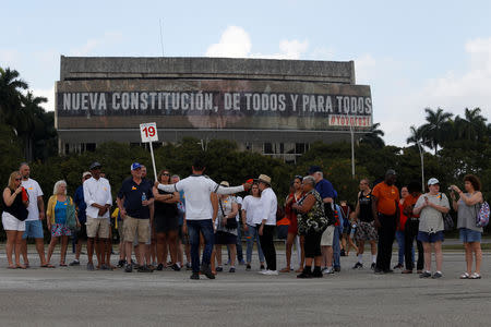 Tourists gather in front of the National Theatre which displays a banner that reads in Spanish: "New Constitution, of all and for all", in Havana, Cuba, February 18, 2019. REUTERS/Stringer. Picture taken on February 18, 2019.