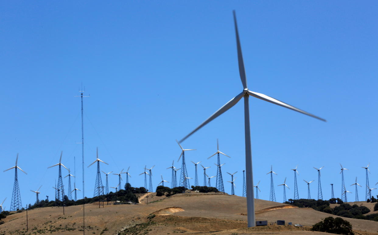 A couple of dozen wind turbines are seen at a wind farm.