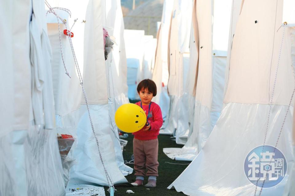 紅衣男童持黃色氣球穿梭玩樂，與白色帳篷形成強烈對比。