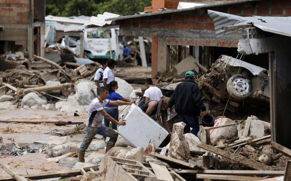 People rescue belongings in Mocoa, Colombia, Sunday, April 2, 2017. A grim search for the missing resumed at dawn Sunday in southern Colombia after surging rivers sent an avalanche of floodwaters, mud and debris through a city, killing at least 200 people and leaving many more injured and homeless. (AP Photo/Fernando Vergara)