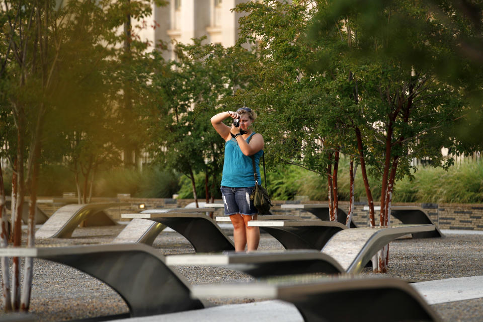 A visitor takes pictures at the permanent outdoor Pentagon Memorial in Arlington Va. The 184 stone benches each bear the name of a person who died Sept. 11, 2001, in the terrorist attack on the Pentagon. Together they comprise the permanent outdoor Pentagon Memorial, created to honor family members and friends killed both in the building and on American Airlines Flight 77. The Pentagon was the first of the three attack sites to open an official memorial. It was dedicated Sept. 11, 2008, and is open 24 hours a day, 365 days a year. (AP Photo/Jose Luis Magana)