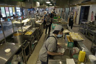 Staff Carol Wong, foreground, cleans dishes at Dignity Kitchen in Hong Kong on Nov. 17, 2020. Located smack in the middle of Hong Kong's bustling Mong Kok neighborhood, Dignity Kitchen offers an array of mouthwatering Singaporean fare. But what sets Dignity Kitchen apart from other restaurants in the city is that it is a social enterprise, almost entirely staffed by employees with physical or mental disabilities. (AP Photo/Vincent Yu)
