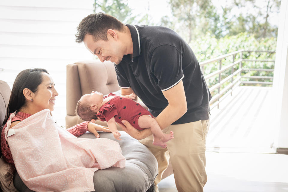 Father of a baby delivering his daughter in the arms of her mother who is preparing to breastfeed her. High quality photo