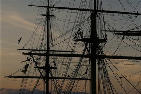 A seagull flies past the HMS Warrior during sunset at the Historic Dock Yard in Portsmouth November 26, 2013. The British shipbuilding industry has been through a turbulent time after defence contractor BAE Systems announced in November that it planned to lay off 1,775 ship workers across the UK. The cuts signal the end of more than 500 years of shipbuilding in Portsmouth on England's south coast. REUTERS/Stefan Wermuth