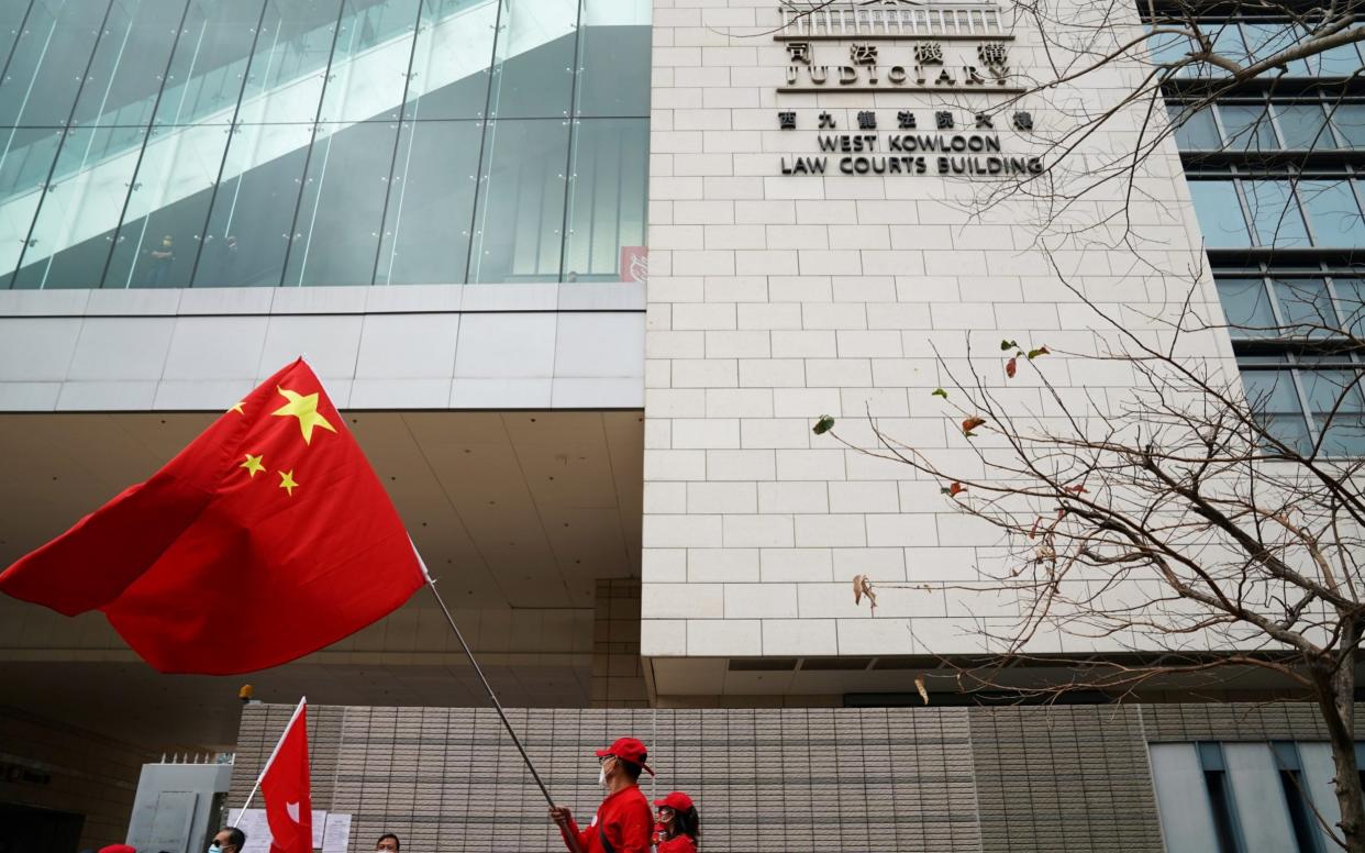 A pro-government supporter holds a Chinese flag outside a court in Hong Kong - Reuters