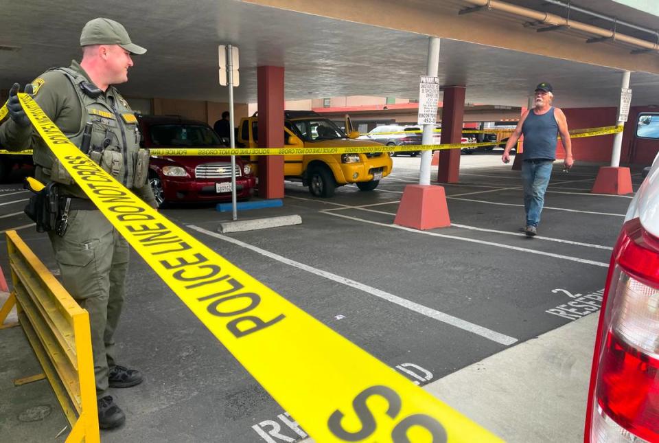 Sacramento Park Ranger Dobbs lifts police line tape as a witnesses exits the scene where a yellow Nissan pickup truck, its tire flattened in a police chase, sits abandoned in an Alhambra Boulevard parking lot on Friday. nlevine@sacbee.com