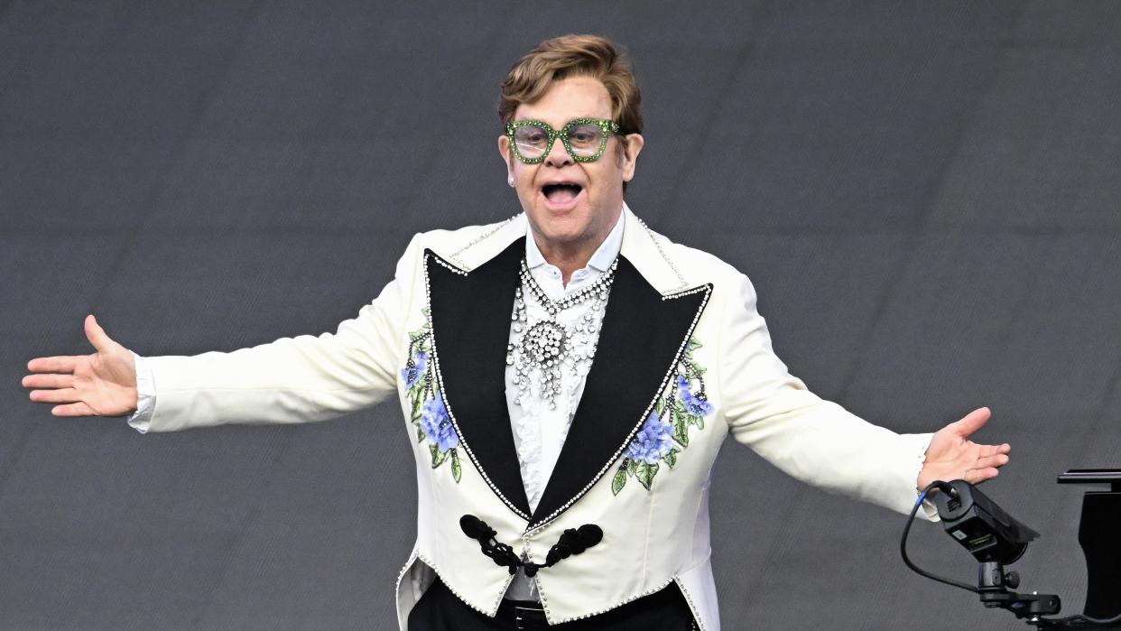  Elton John performs on stage wearing a bejewelled jacket and oversized green glasses ahead of Glastonbury 2023. 