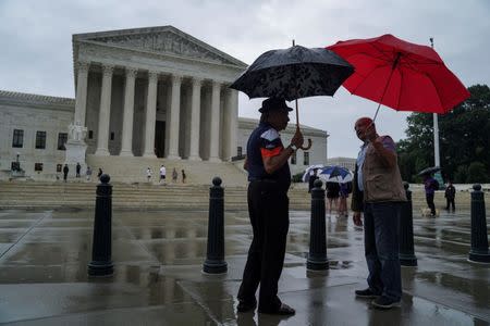 Men walk with umbrellas prior to the U.S. Supreme Court's decision to impose limits on the ability of police to obtain cellphone data pinpointing the past location of criminal suspects, outside the U.S. Supreme Court in Washington, U.S., June 22, 2018. REUTERS/Toya Sarno Jordan