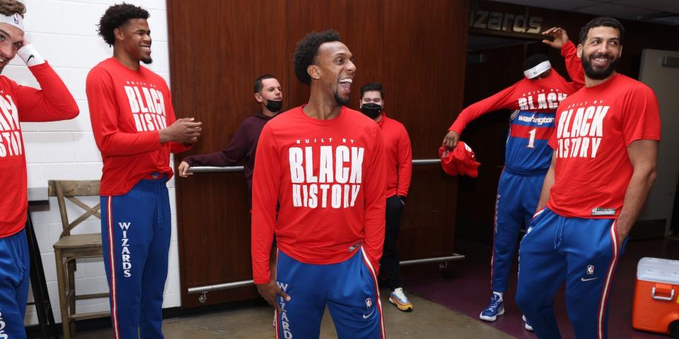 Ish Smith laughs while surrounded by smiling teammates in the Wizards locker room in 2022.