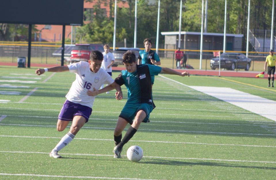 Caleb Swenson of the Islands soccer team moves the ball downfield with Tomas Gallo of Bainbridge defending in a first round playoff matchup on April 15.