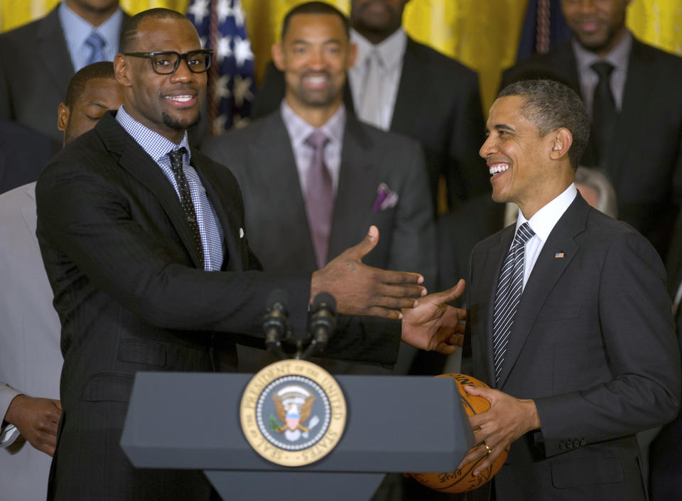 LeBron James in a suit and tie next to Barack Obama at the president's podium in the White House. 