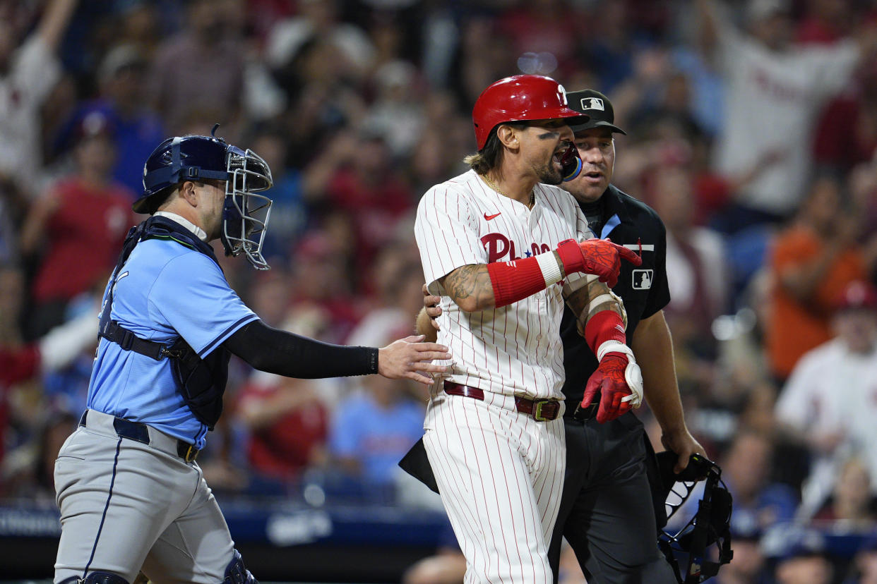 Philadelphia Phillies' Nick Castellanos, center right, reacts after he was hit by a pitch from Tampa Bay Rays' Edwin Uceta as Logan Driscoll, left, and umpire John Libka hold back Castellanos during the eighth inning of a baseball game, Tuesday, Sept. 10, 2024, in Philadelphia. (AP Photo/Derik Hamilton)