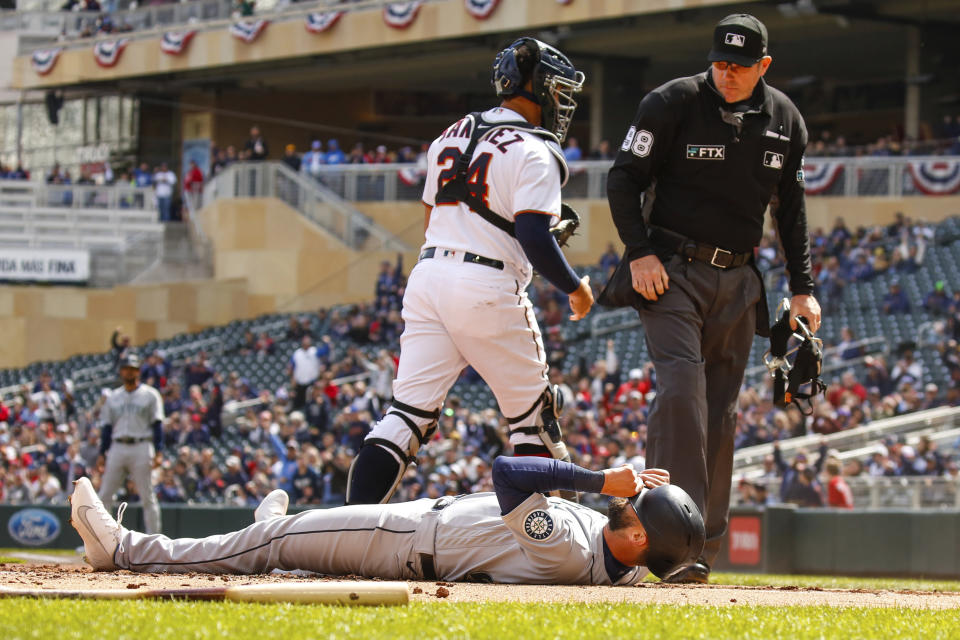 Seattle Mariners' Jesse Winker (27) lies on the ground after being tagged out at home to end the inning against the Minnesota Twins during the first inning of a baseball game, Sunday, April 10, 2022, in Minneapolis. (AP Photo/Nicole Neri)