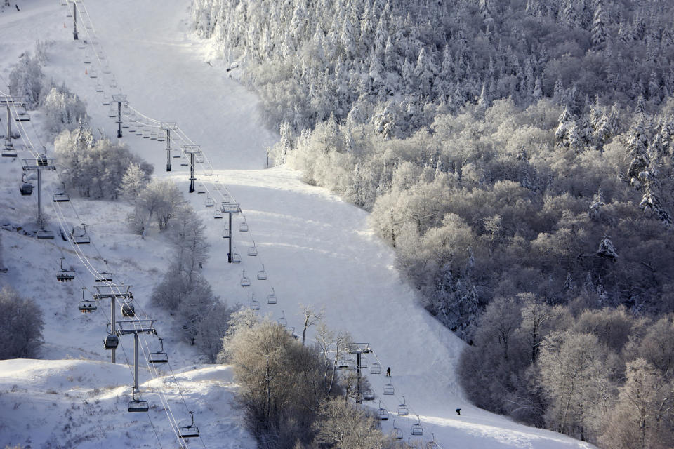 a snowy hillside with ski lifts rising up the side.