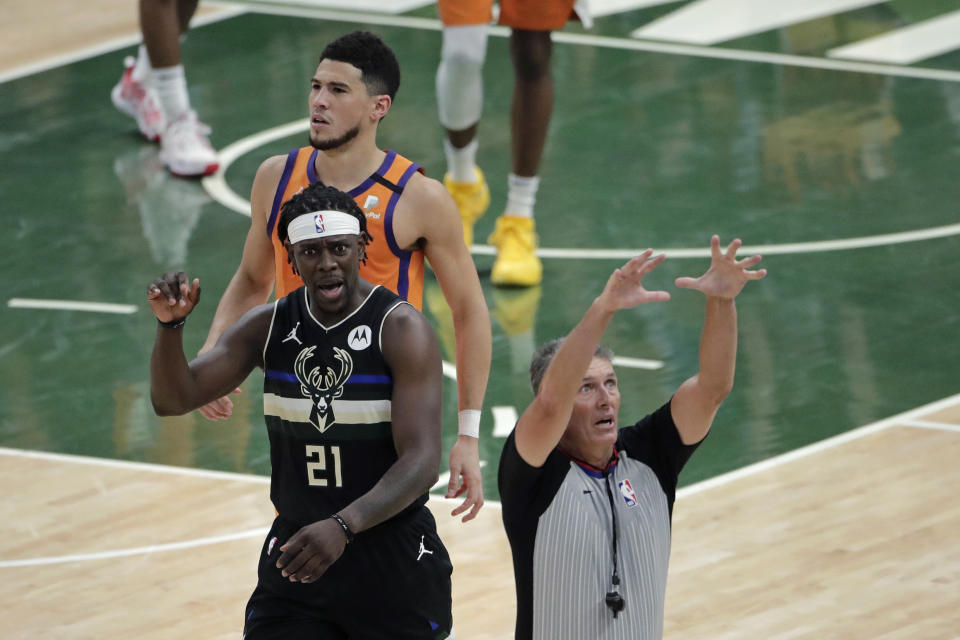 Milwaukee Bucks guard Jrue Holiday (21) reacts in front of Phoenix Suns guard Devin Booker during the first half of Game 6 of basketball's NBA Finals Tuesday, July 20, 2021, in Milwaukee. (AP Photo/Aaron Gash)