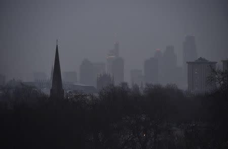 City of London financial district skyscrapers are seen behind a church spire at dawn in London, January 8, 2015. REUTERS/Toby Melville