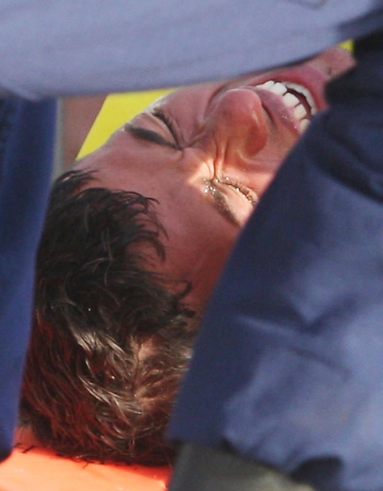 CORRECTS TO SHOW HE IS THE THIRD REFUGEE - The third and last Cuban refugee grimaces in pain while being off-loaded from the Coast Guard boat at the United States Coast Guard Base Key West Friday, Feb. 21, 2014. The three migrants left Jibacoa, Cuba, on Tuesday. One made it to Key West more than nine hours later and told authorities that he lost sight of the others about 60 miles south of Key West. A second was found by a boater Thursday. (AP Photo/Key West Citizen, Mike Hentz)