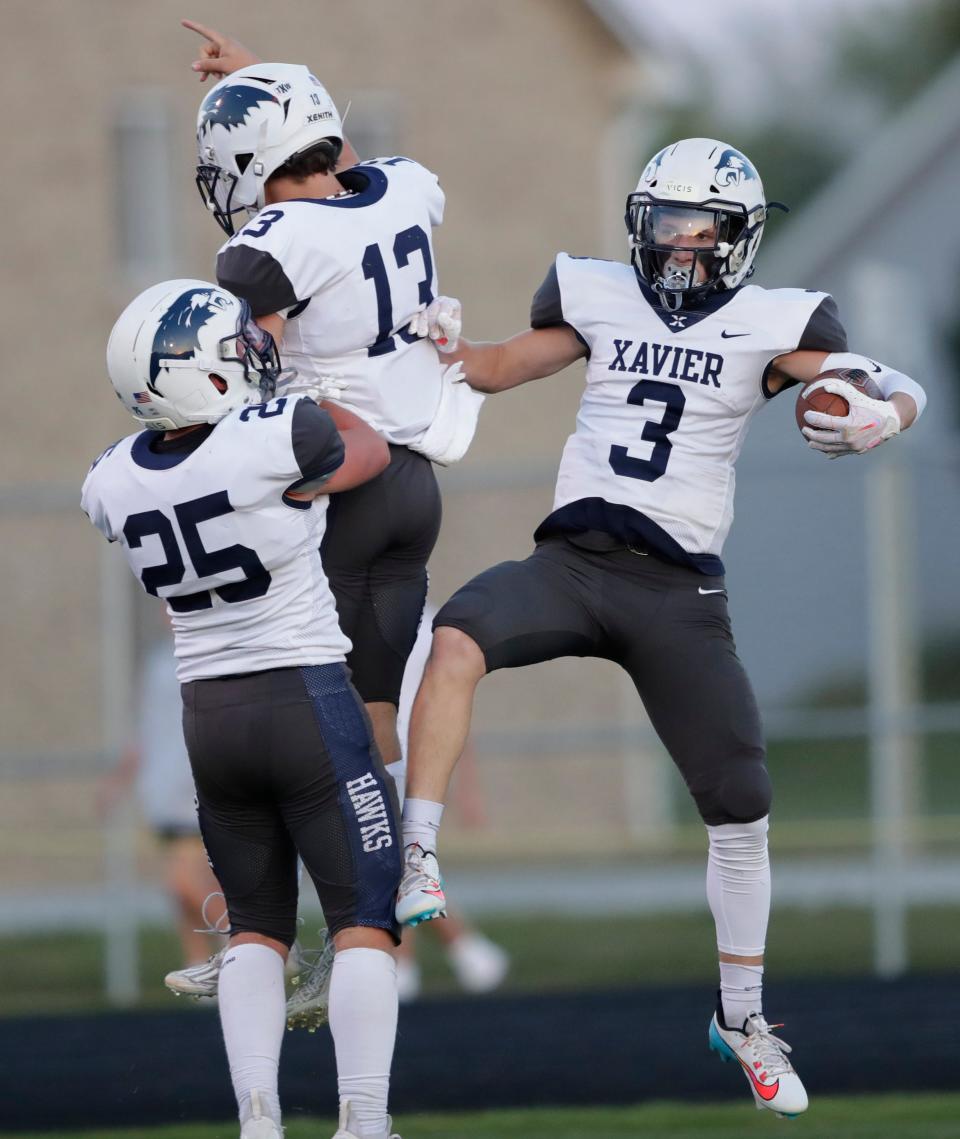 Xavier's Isaiah Des Jardins (3) celebrates scoring a 68-yard touchdown with teammates Carter McGlone (25) and Matthew Potter (13) against Freedom on Sept. 1 in Freedom.