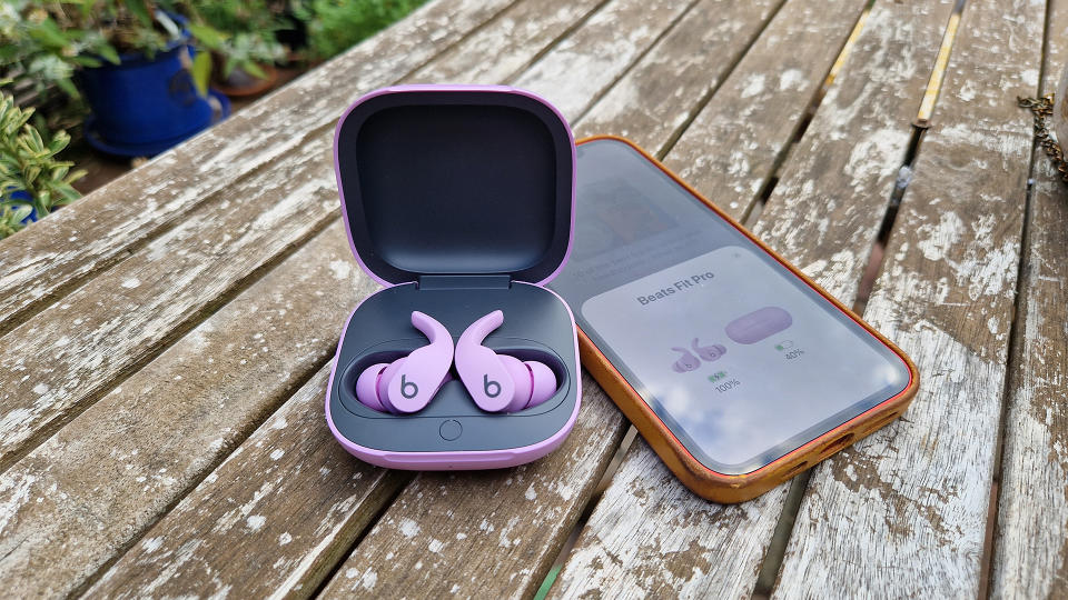 Beats Fit Pro wireless earbuds with iPhone 12 on table outside