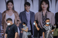 People wearing face masks to help protect against COVID-19 walk past an advertising billboard at a subway station during the morning rush hour in Beijing, Wednesday, Aug. 4, 2021. China's worst coronavirus outbreak since the start of the pandemic a year and a half ago escalated Wednesday with dozens more cases around the country, the sealing-off of one city and the punishment of its local leaders. (AP Photo/Mark Schiefelbein)