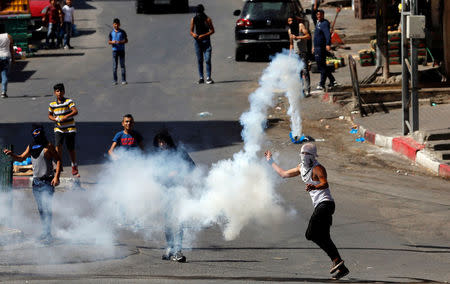 A Palestinian protester uses a sling to hurl back a tear gas canister fired by Israeli troops during clashes in Hebron in the occupied West Bank, June 29, 2018. REUTERS/Mussa Qawasma