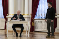 Ukrainian President Volodymyr Zelenskyy watches as President Joe Biden signs the guest book at Mariinsky Palace during a surprise visit, Monday, Feb. 20, 2023, in Kyiv. (AP Photo/Evan Vucci, Pool)
