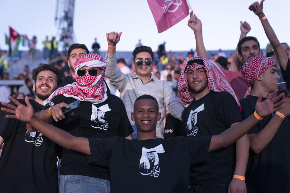 Jordanian men wearing the traditional Jordanian red and white checkered scarf and T-shirts with pictures that depict Jordan's Crown Prince Hussein, dance and sing during a concert at a sports stadium in Amman, Jordan, Monday, May 29, 2023. The free concert featuring well-known Arab singers, including Egyptian star Tamer Hosny, was part the celebrations leading up to the wedding of Crown Prince Hussein and his fiancee, Saudi architect Rajwa Alseif later this week. (AP Photo/Nasser Nasser)