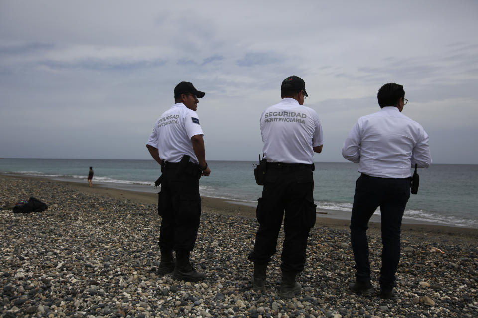 Prison guards stand on the shore of the Pacific Ocean during a media tour of the now closed Islas Marias penal colony, Mexico, Saturday, March 16, 2019. In a place where most of the few dozen prisoners who attempted to escape drowned, the Environment Department says it is thinking about offering survival courses, bird watching, nature walks and arts programs. (AP Photo/Rebecca Blackwell)