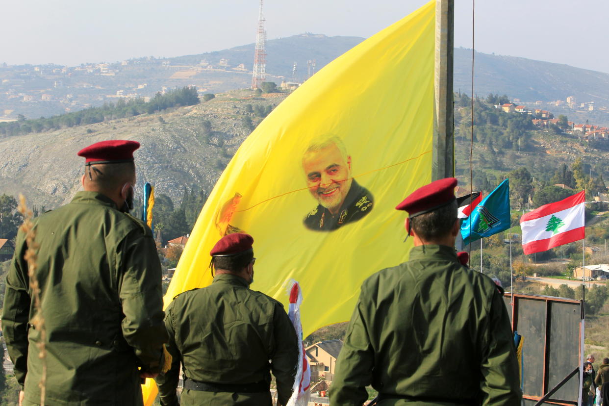 A flag with an image of senior Iranian military commander Qassem Soleimani is displayed by Hezbollah soldiers in Lebanon during a ceremony marking the first anniversary of his killing