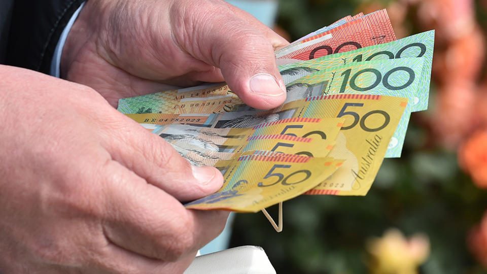 World Health Organisation has warned the coronavirus could spread through bank notes. Pictured is a man's hands holding Australian currency.