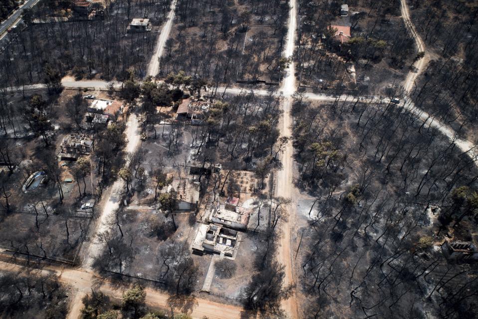 This Wednesday, July 25, 2018 aerial photo shows burnt houses and trees following a wildfire in Mati, east of Athens. Frantic relatives searching for loved ones missing in Greece's deadliest forest fire in decades headed to Athens' morgue on Thursday, July 26, 2018 as rescue crews and volunteers continued searches on land and at sea for potential further victims. (Antonis Nikolopoulos/Eurokinissi via AP)