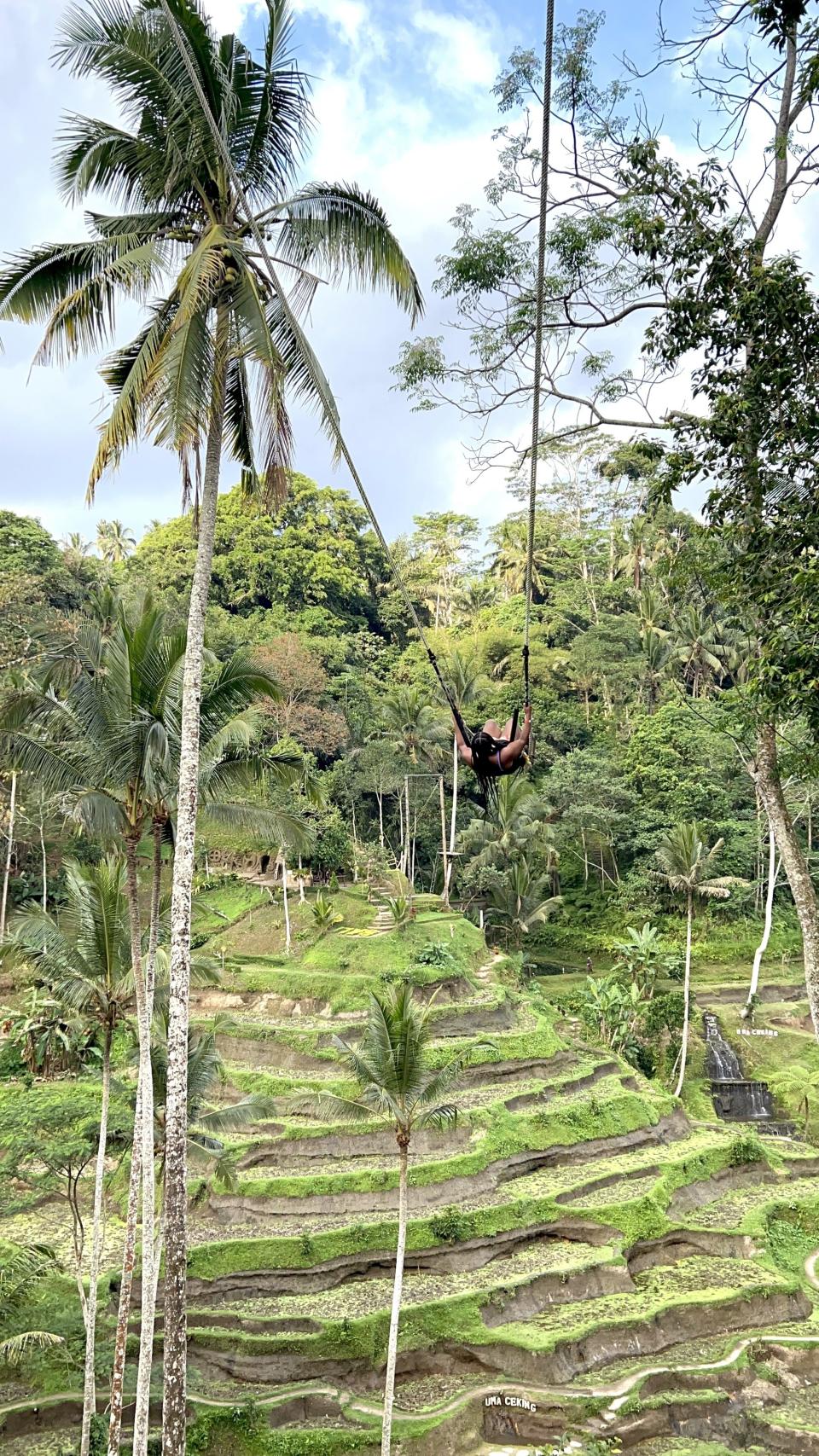 A girl (me) swinging on a huge jungle swing over rice fields in Bali