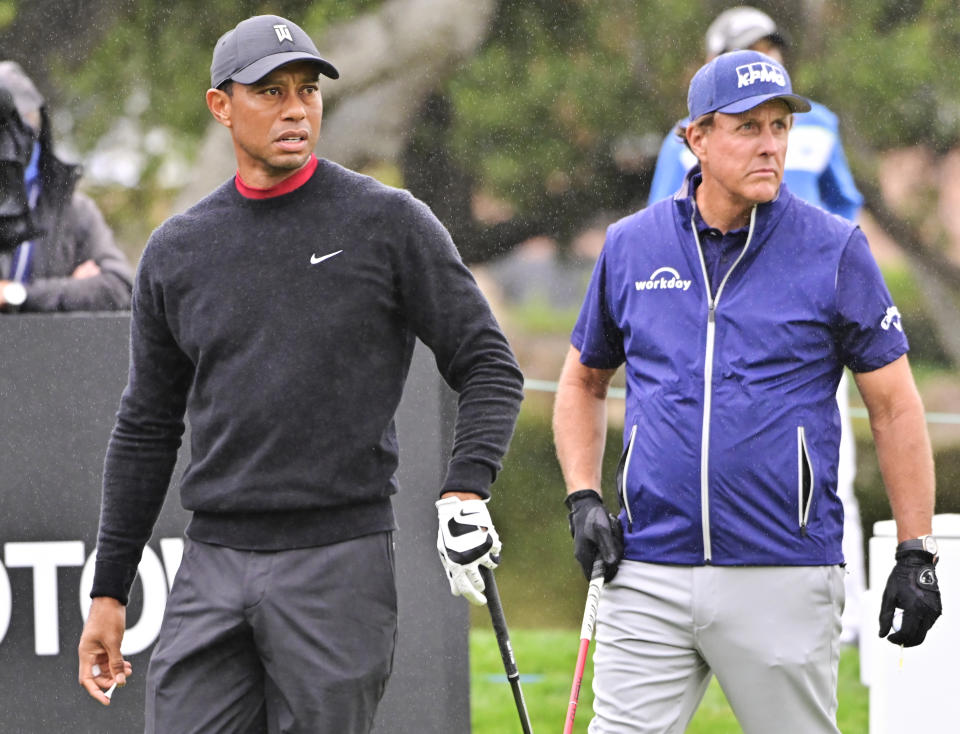 Tiger Woods (pictured left) hits a tee shot as Phil Mickelson (pictured right) watches.