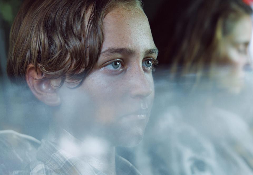 jodie in the chosen one sitting in a car with his mother in the background