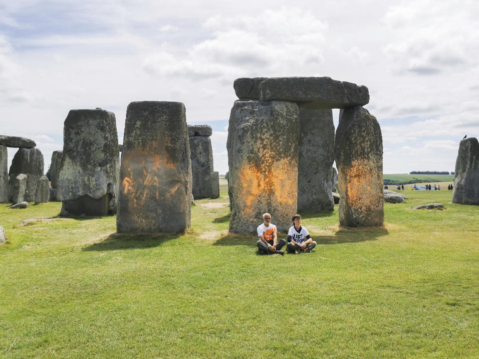 In this handout photo, Just Stop Oil protesters sit after spraying an orange substance on Stonehenge, in Salisbury, England, Wednesday June 19, 2024. (Just Stop Oil via AP)