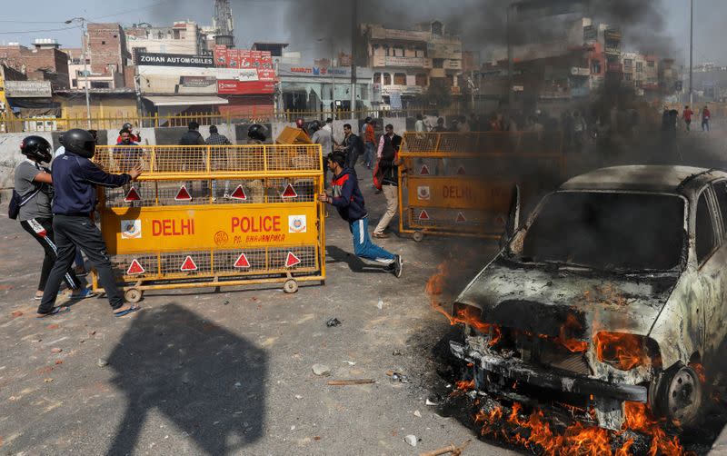 People supporting a new citizenship law push police barricades during a clash with those opposing the law in New Delhi