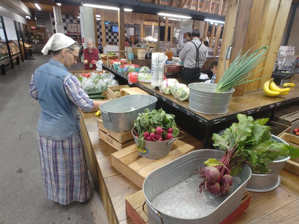 A woman checks out items at Harvest Hill Produce at Jim's Farmers Market on Friday, June 9, 2023.